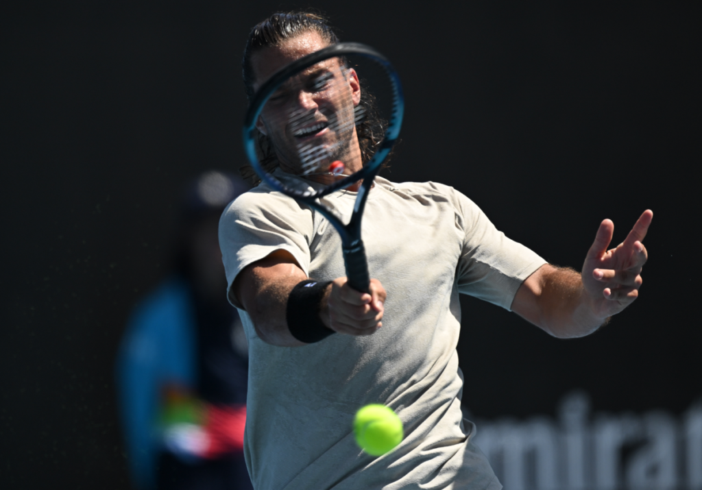 Alexis Galarneau's racket passes in front of his face as he follows through on a forehand.