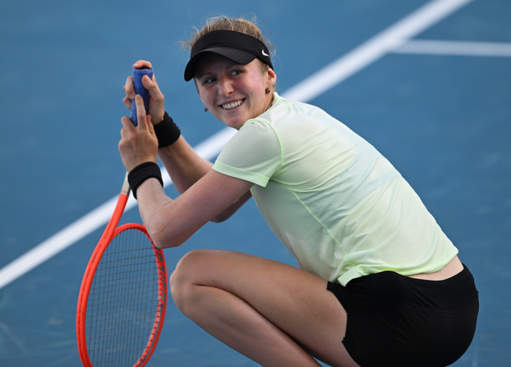 Katherine Sebov kneels on the court and turns and smiles.